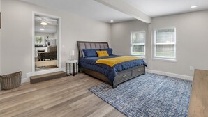 A bedroom with a bed, a rug, a window, and a door leading to a bathroom. - Classy 4BR Family Home Near FSU (Tallahassee)