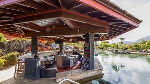 An outdoor pool area with a covered seating area, a bar, and a signboard. - Ocean View Studio at HBR, A/C Included (Princeville)