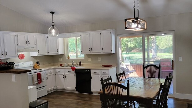A spacious kitchen with white cabinets, a central island, and a dining area with wooden chairs and a table. - Cute, pet-friendly home in quiet neighborhood. Close to state parks & downtown. (Rockville)