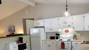 A modern kitchen with white cabinets, a wooden dining table, and a hanging light fixture. - Cute, pet-friendly home in quiet neighborhood. Close to state parks & downtown. (Rockville)