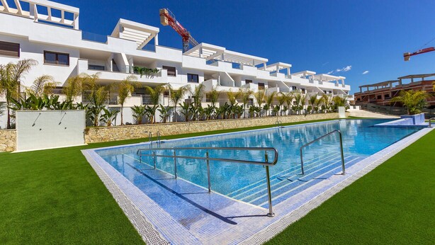 A modern hotel with a swimming pool, a covered outdoor area, and a view of the construction site in the background. - Cozy apartment in Finestrat with WiFi (Finestrat)