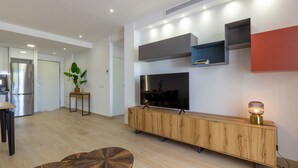 A modern living room with a large flat-screen TV, wooden console, and built-in shelves. - Cozy apartment in Finestrat with WiFi (Finestrat)