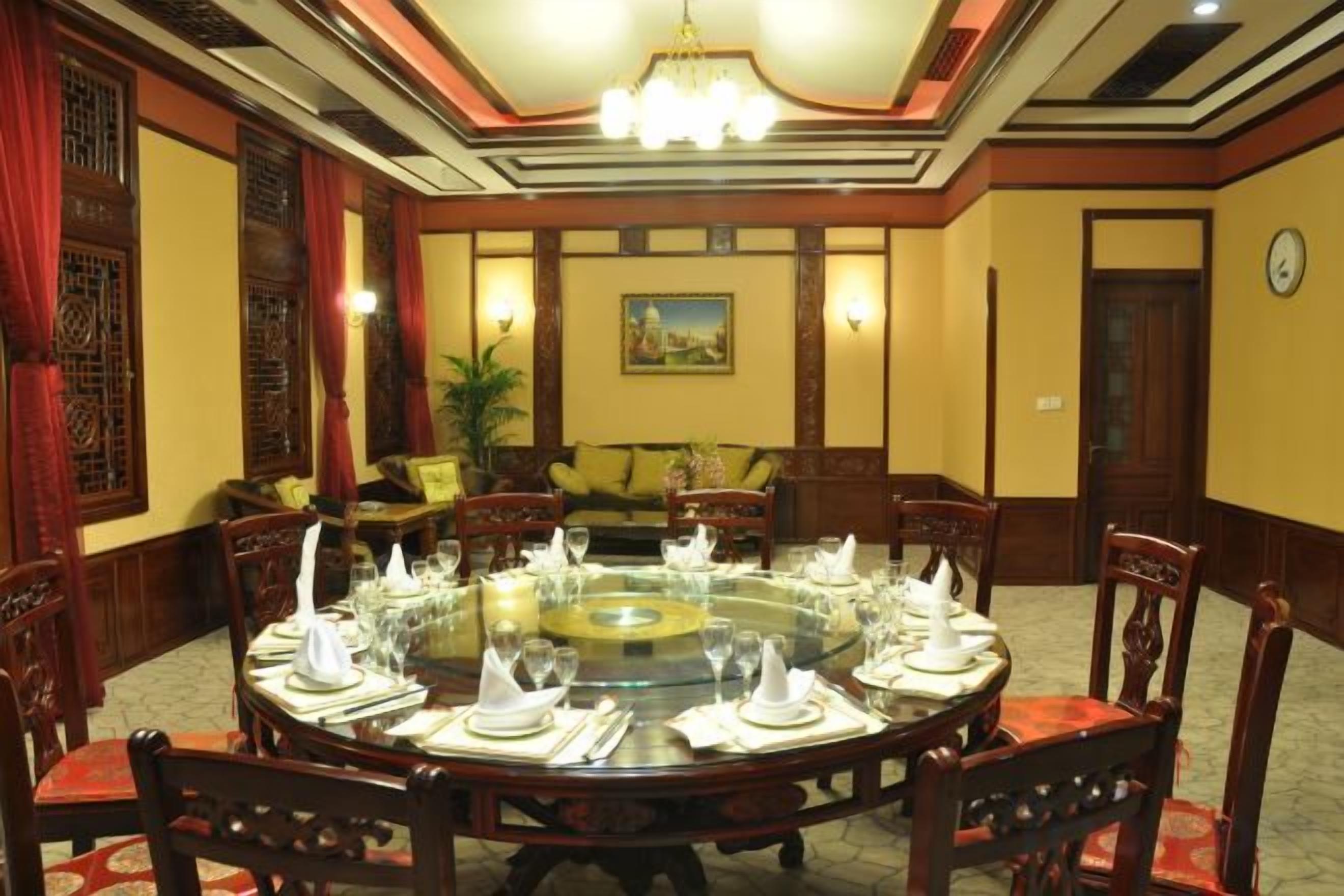 Un comedor formal con una mesa redonda dispuesta para una comida, rodeada de sillas de madera.