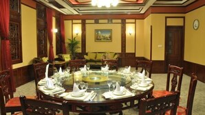 Comedor con una mesa redonda de vidrio dispuesta para una comida, rodeado de sillas de madera.