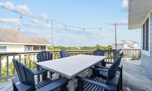 An outdoor deck with a table and chairs, surrounded by a wooden railing, under a clear sky.