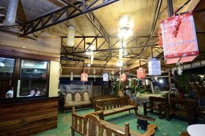 A rustic interior with wooden furniture, hanging lights, and a bar area.