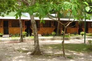 A building with a covered outdoor area, a tree in the foreground, and a paved walkway.