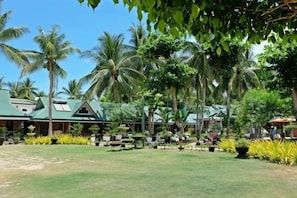 A resort with a green-roofed building, palm trees, and a well-maintained lawn. - Dumaluan Beach - Marilou Resort (Panglao Municipality)