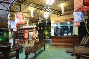 An indoor space with wooden benches, a high ceiling with metal beams, and hanging decorations.