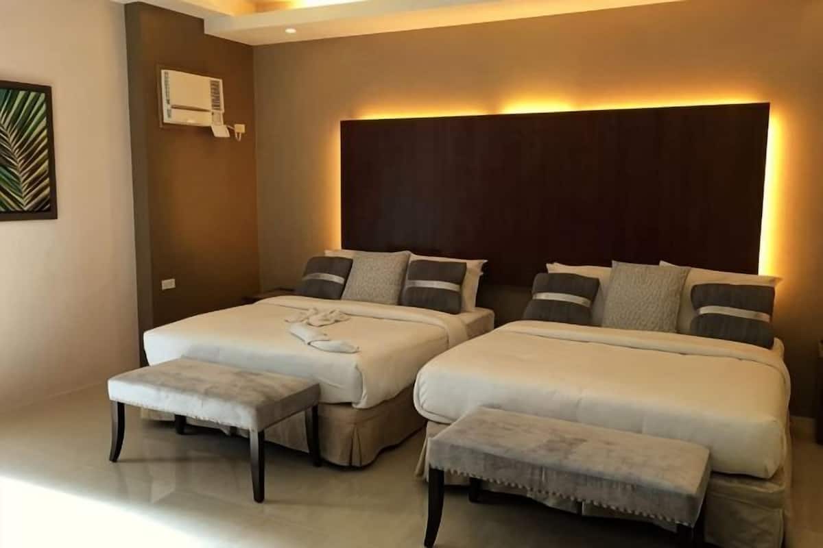 Une chambre d’hôtel avec deux lits, une grande tête de lit et un petit coin salon.
