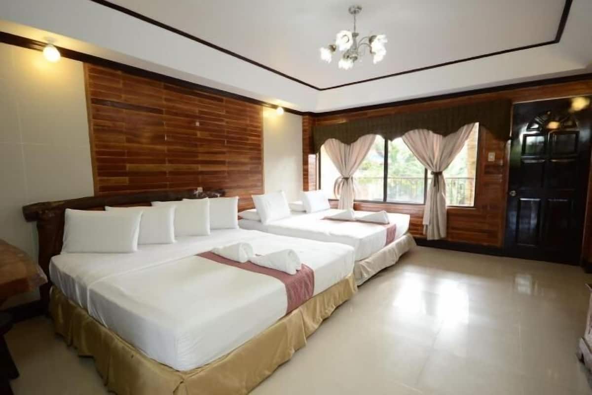 Une chambre d’hôtel avec trois lits, des boiseries, un lustre et une porte coulissante.