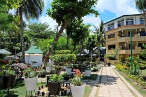 A hotel courtyard with potted plants, a pathway, and a building with multiple floors.