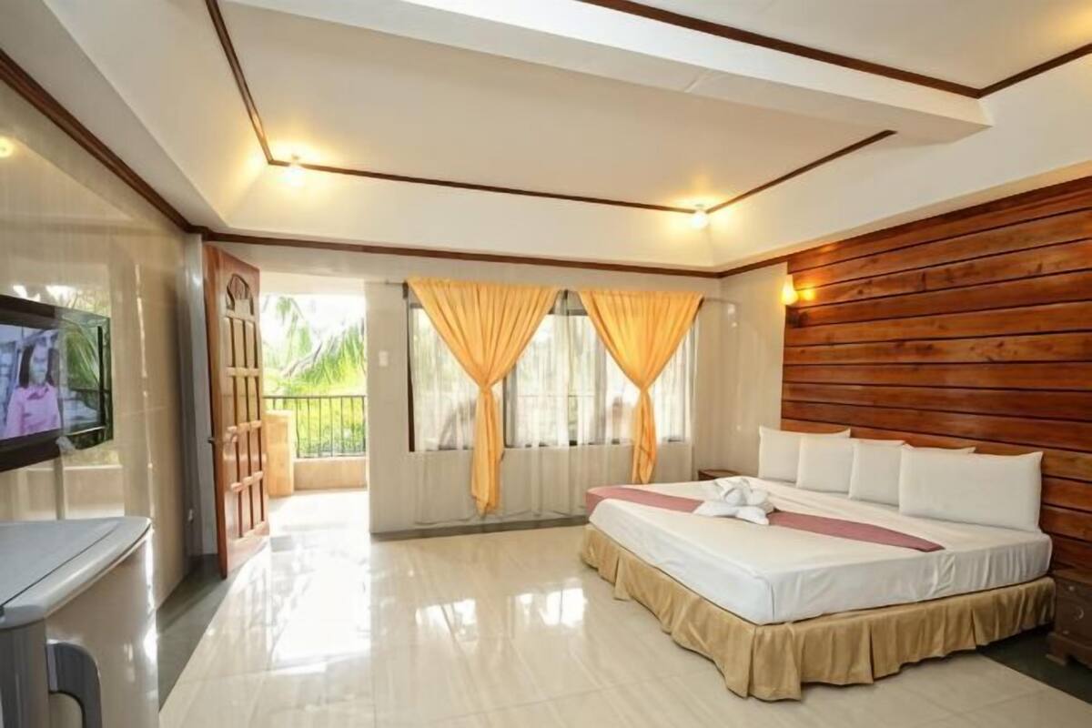 Une chambre à coucher avec un lit, des rideaux, un téléviseur et un mur en bois.