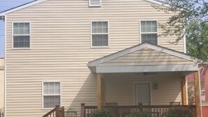 A two-story house with a front porch, a small deck, and a staircase leading to the entrance. - Your Centrally Located C-Ville Home Away From Home Vacation Rental  (Charlottesville)