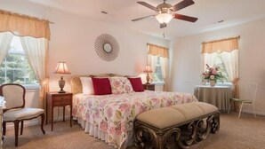 A bedroom with a bed, two bedside tables, a chair, a ceiling fan, and a window with curtains. - Your Centrally Located C-Ville Home Away From Home Vacation Rental  (Charlottesville)