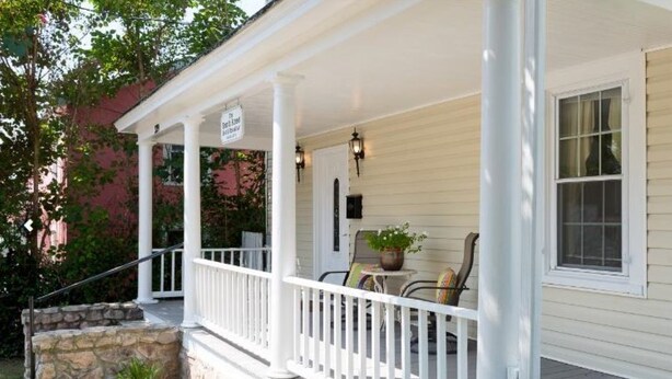 A porch with a white railing, a table with chairs, and a potted plant. - Your Centrally Located C-Ville Home Away From Home Vacation Rental  (Charlottesville)