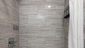 A modern bathroom with a freestanding bathtub, a showerhead, and a towel rack. - Classic King Room - Sleeps 2 (Monterey)