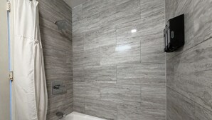 A modern bathroom with a bathtub, shower, and a towel rack. - Signature King Room - Larger Layout - Sleeps 2 (Monterey)
