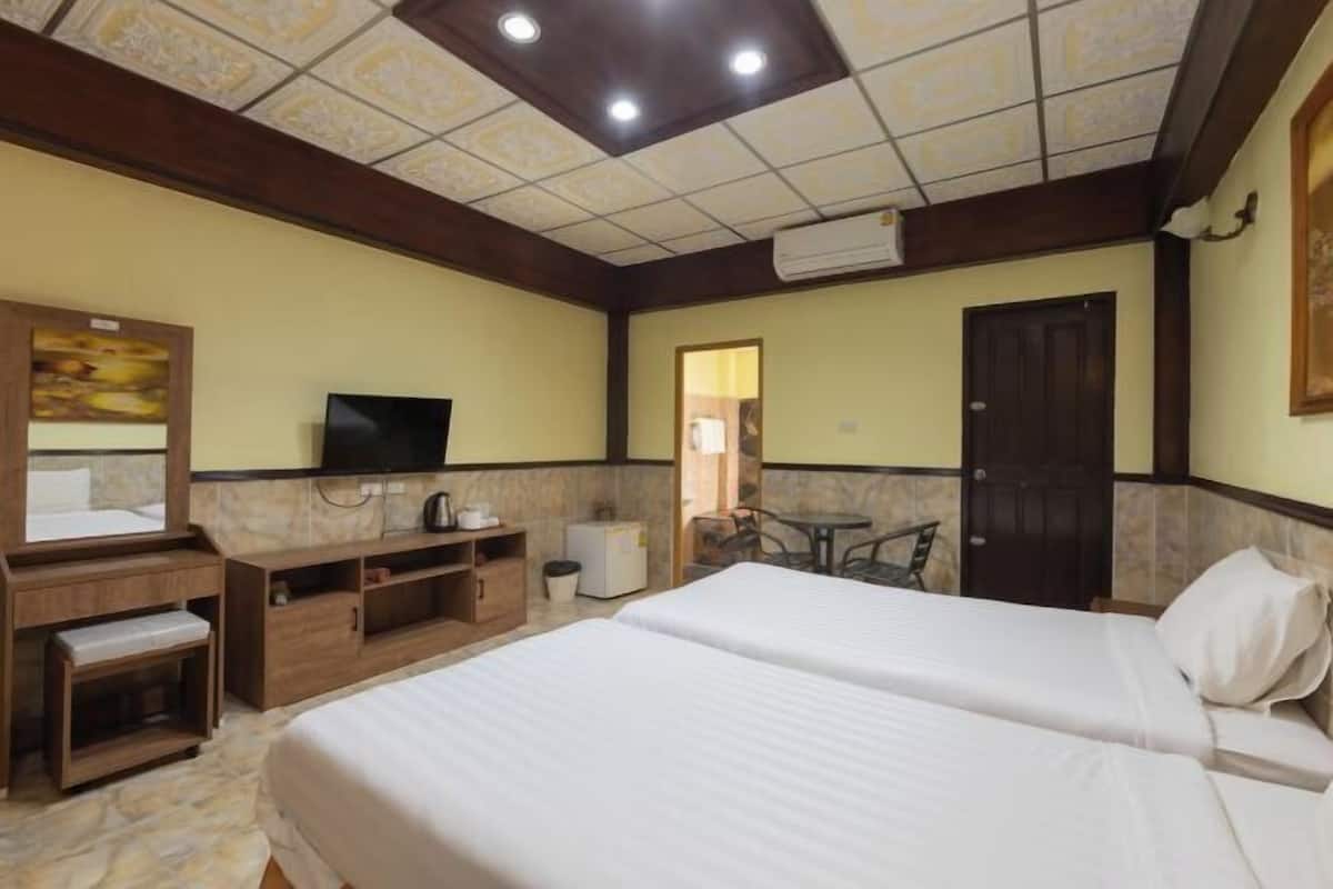 Quarto de hotel com uma cama grande, televisão, escrivaninha com cadeira e uma pequena mesa com cadeiras.