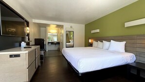 Hotelkamer met een bed, een bureau, een spiegel en een badkamer die door een open deur zichtbaar is.