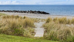 Une plage avec une promenade en bois qui mène à une digue rocheuse.