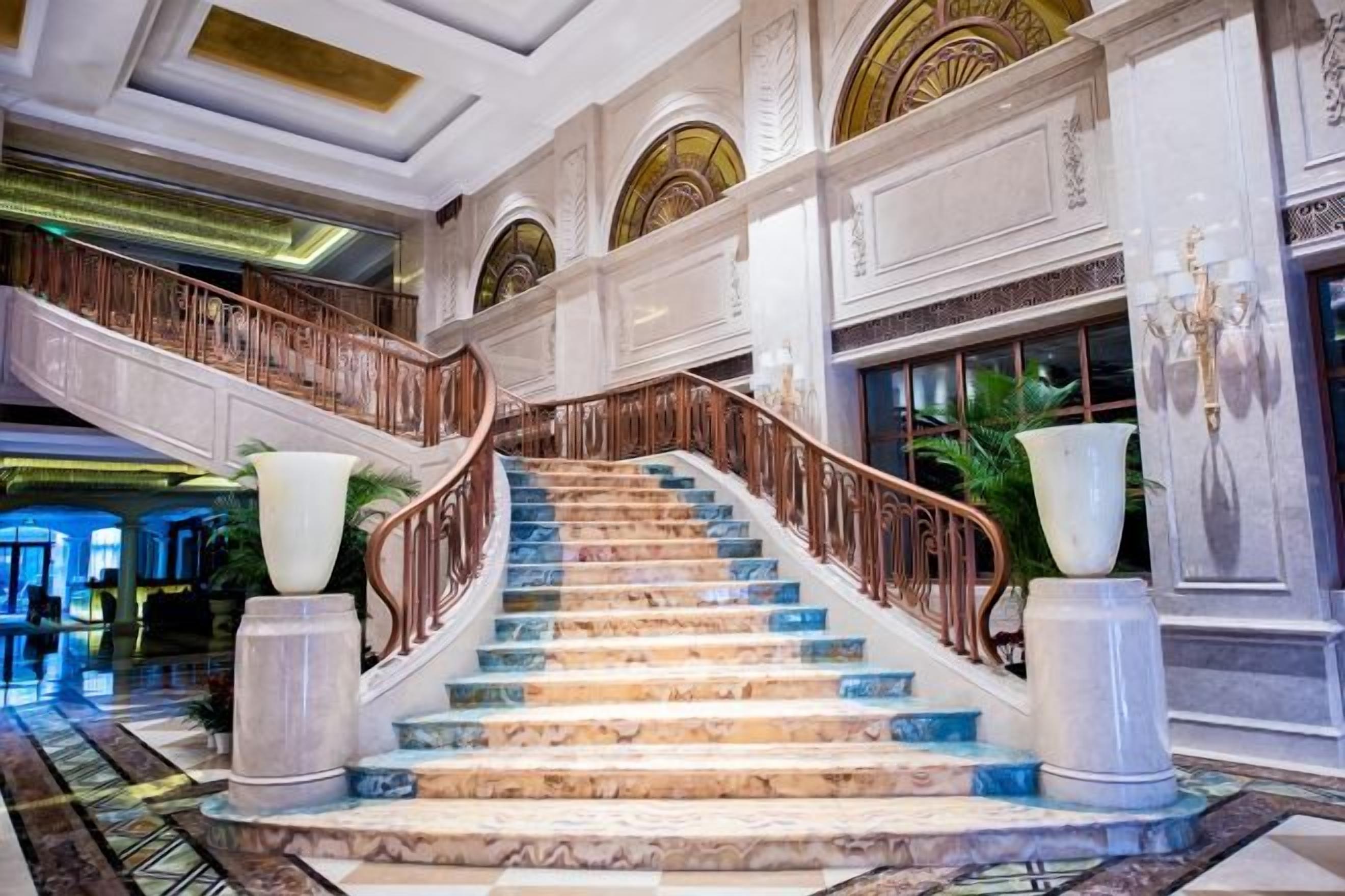 Un magnifique escalier en marbre, avec des marches de marbre et une rampe en bois, menant à l’étage supérieur.