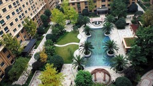 Une piscine sur le toit, entourée d’une végétation luxuriante et de bâtiments modernes.
