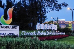 Een bord met de tekst 'Chengdu Makes Dreams Come True' en 'SU Games', omringd door groen.