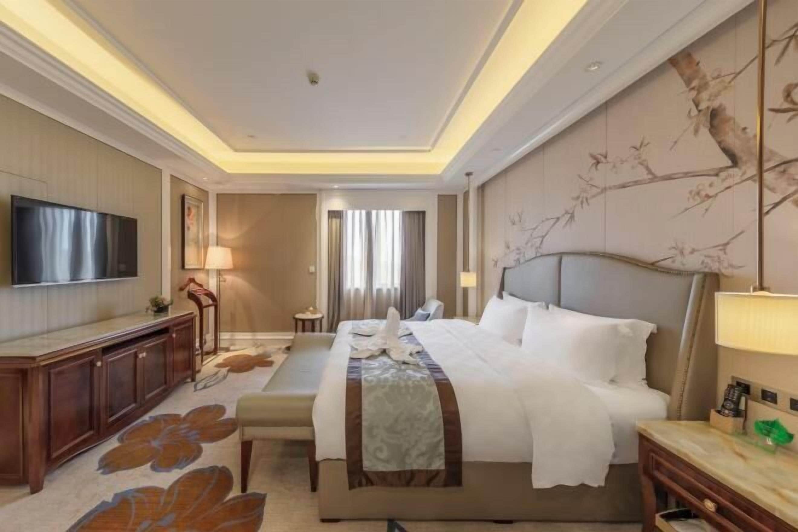 Una habitación de hotel con una cama grande, televisión, escritorio y silla.