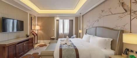 A hotel room with a large bed, a television, a desk, and a chair.