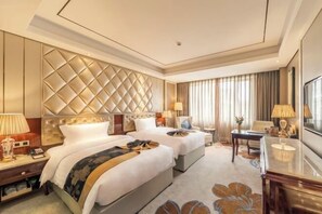 A hotel room with two beds, a large padded headboard, a desk, and a dining area. - Xingchen Hangdu International Hotel (Chengdu)