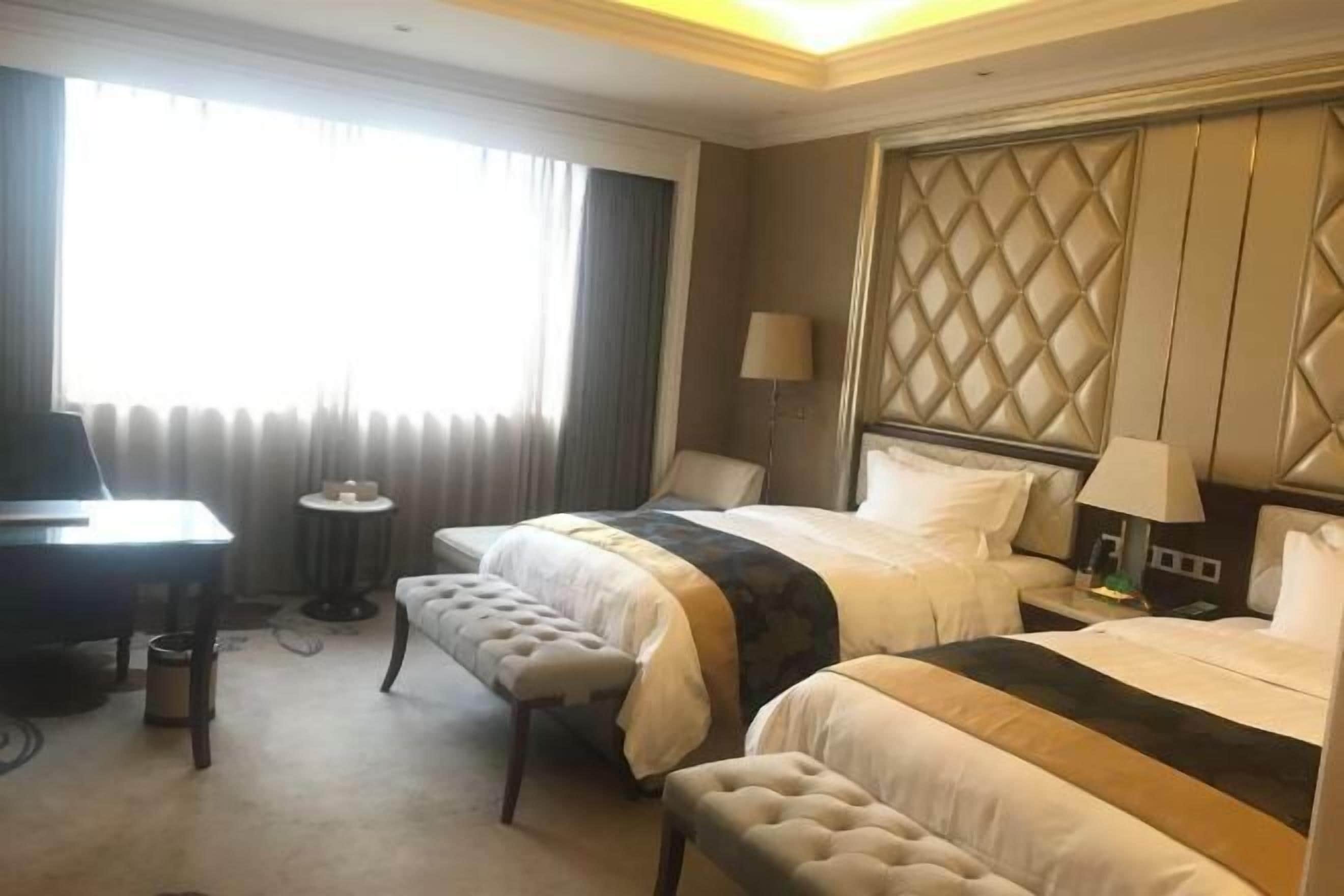 Une chambre d’hôtel avec deux lits, un bureau, une chaise et une petite table.