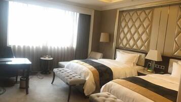 Une chambre d’hôtel avec deux lits, un bureau, une chaise et une petite table.