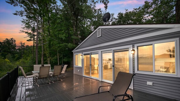 Een terras met tuinmeubilair, een schotelantenne, en een huis met grote ramen.