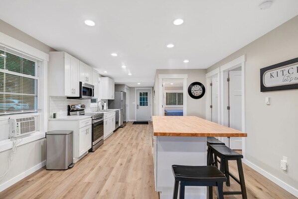 A modern kitchen with white cabinets, a wooden countertop, and a black bench.