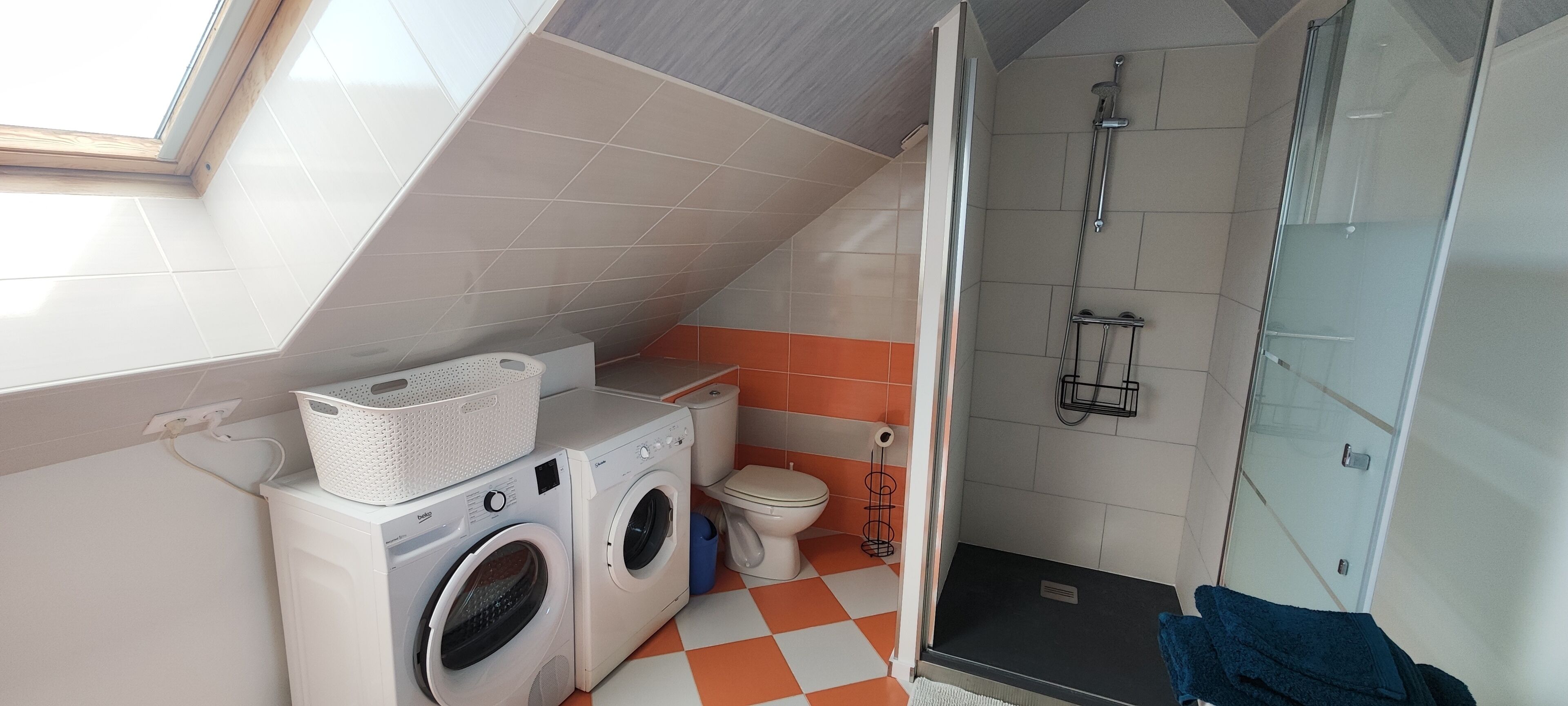 Un espace buanderie compact comprenant un lave-linge, un sèche-linge et un petit évier.