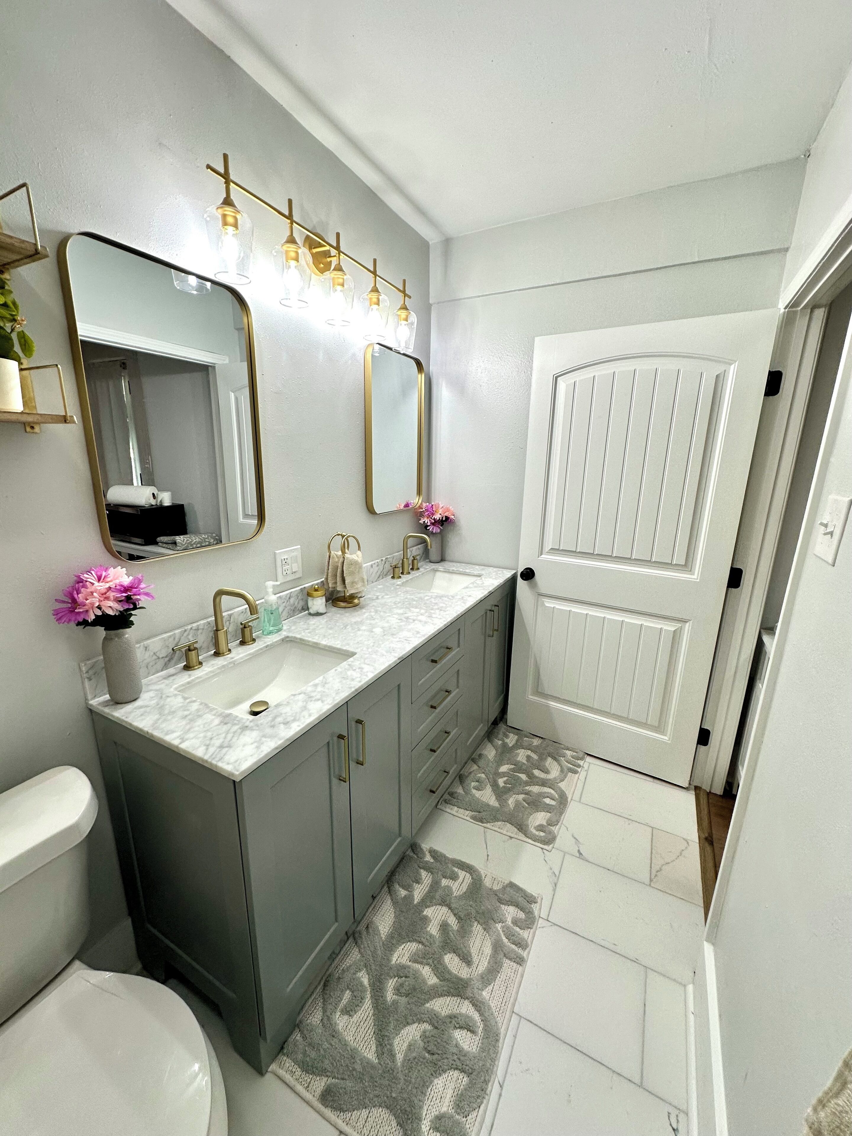 Un baño con inodoro blanco, lavamanos con encimera de mármol y zona de ducha.