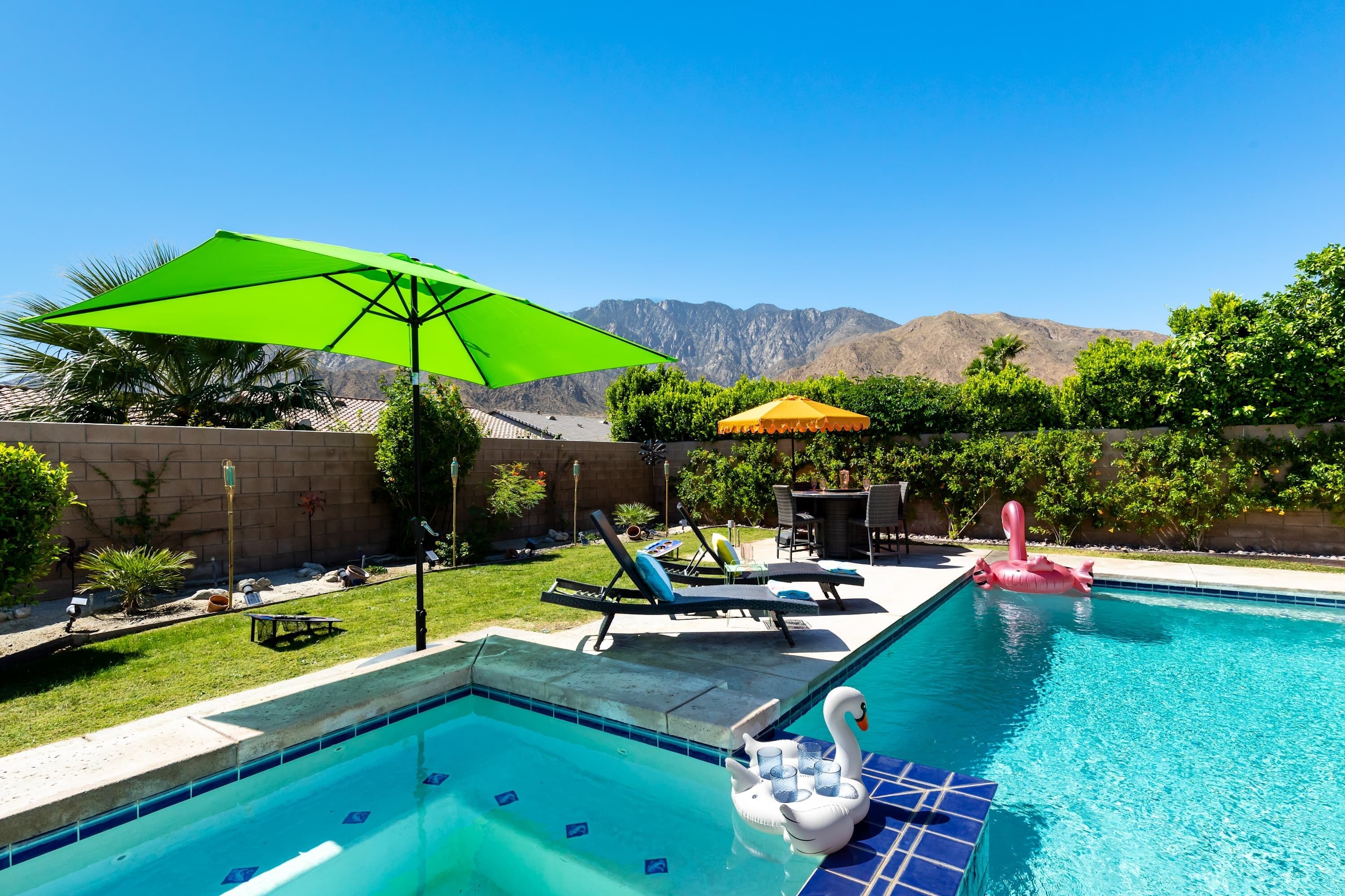 A swimming pool with a swan float, lounge chairs, and umbrellas.