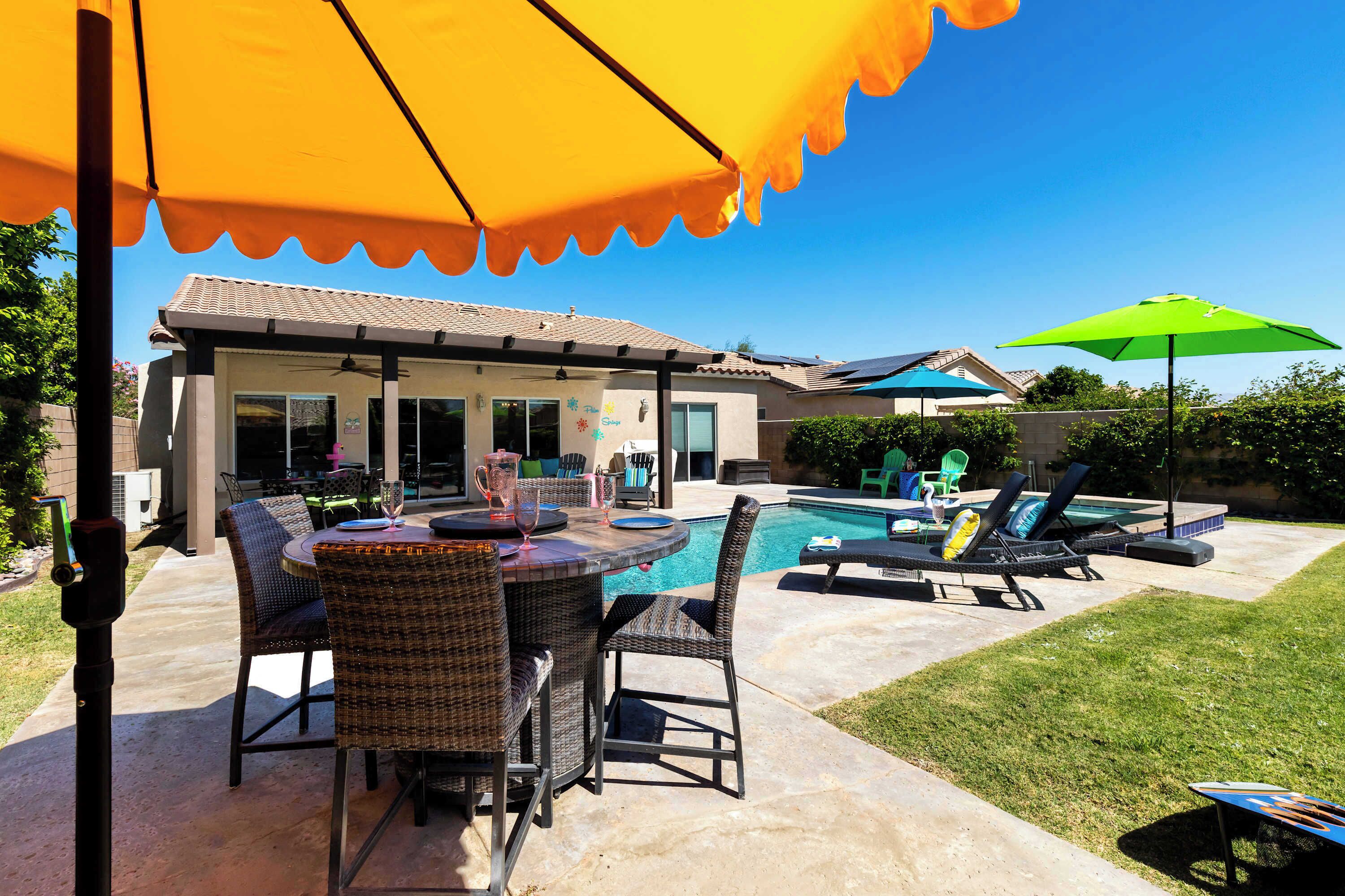 Un jardin avec une piscine, du mobilier d’extérieur et un patio couvert.