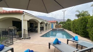 A poolside area with lounge chairs, a pool, and a covered patio. - Ranch Club Estates Retreat with Pool and Dog Run (Palm Springs)