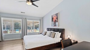 Camera moderna con un letto grande, una ventola a soffitto e vista all'esterno tramite ampie finestre.