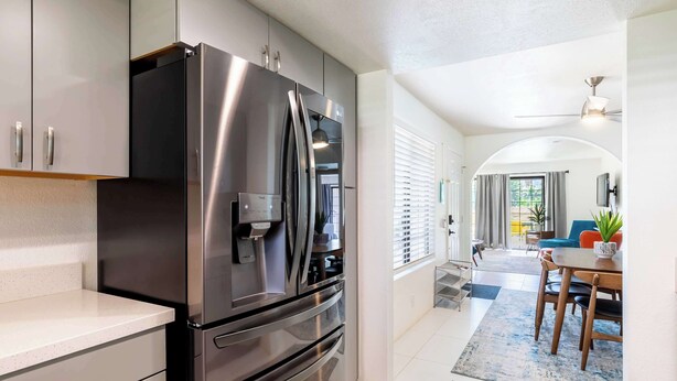 A modern kitchen with stainless steel appliances, a dining area with a table and chairs, and a view into the living room. - Palm Springs 2BR Mountain View Pool Home (Palm Springs)