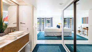 A modern hotel room with a large bed, a bathroom with a large mirror, and a view of the outdoors. - Palm Springs 2BR Mountain View Pool Home (Palm Springs)