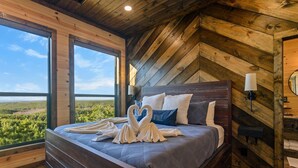 Une chambre avec un grand lit, des murs en bois et une vue sur un paysage verdoyant.