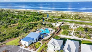 An aerial view of a coastal property with a swimming pool, a road, and a beach in the background. - Fall Break is Coming Up! Coastal Home- Walk,Bike, Golf Cart 2 Pools & Beach.  (Port St. Joe)