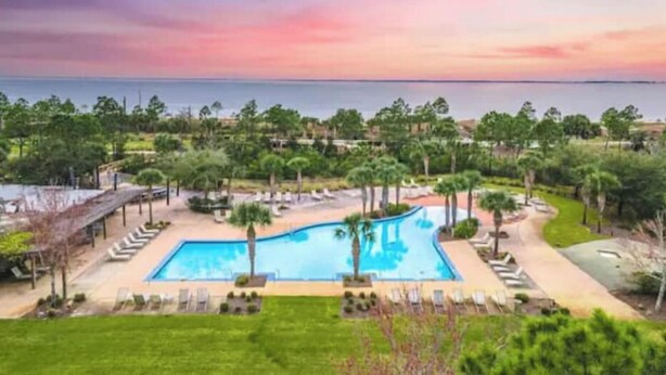 A resort with a large pool, lounge chairs, and a view of the ocean at sunset. - Fall Break is Coming Up! Coastal Home- Walk,Bike, Golf Cart 2 Pools & Beach.  (Port St. Joe)