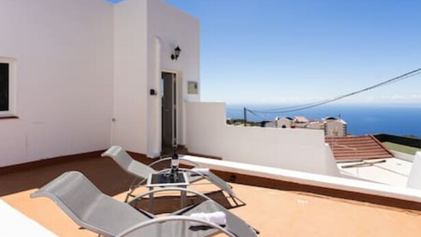 Une chambre d’hôtel moderne avec balcon, un lit et vue sur la mer.