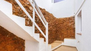 Un escalier avec des rampes blanches menant à une pièce aux murs blancs et au plancher en bois.