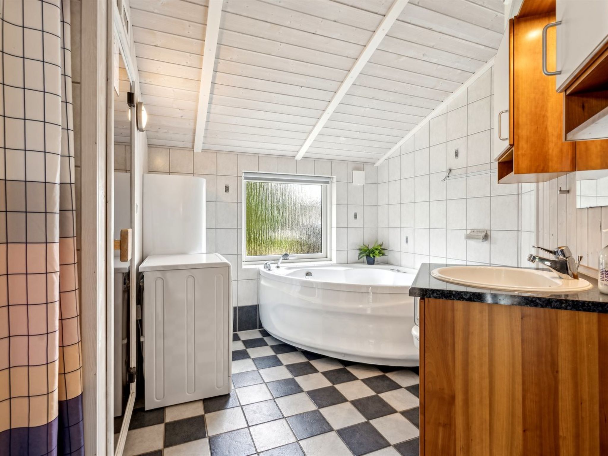 A modern bathroom with a checkered floor, a freestanding bathtub, and a wooden vanity.