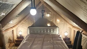 Une chambre confortable située dans les combles, avec un lit, deux lampes de chevet et un attrape-rêves suspendu.